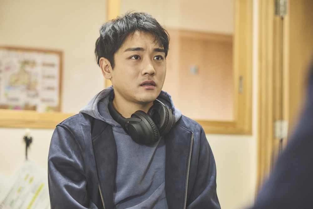 茂木優輝を演じる泉澤祐希。ヘッドホンを首にかけ、戸惑った表情を見せる。