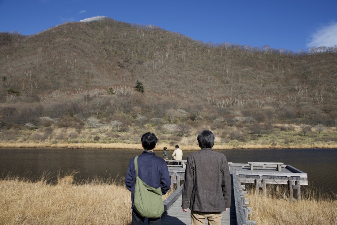 場面写真：山を望む湖畔の桟橋を並んで歩く二人の後ろ姿。