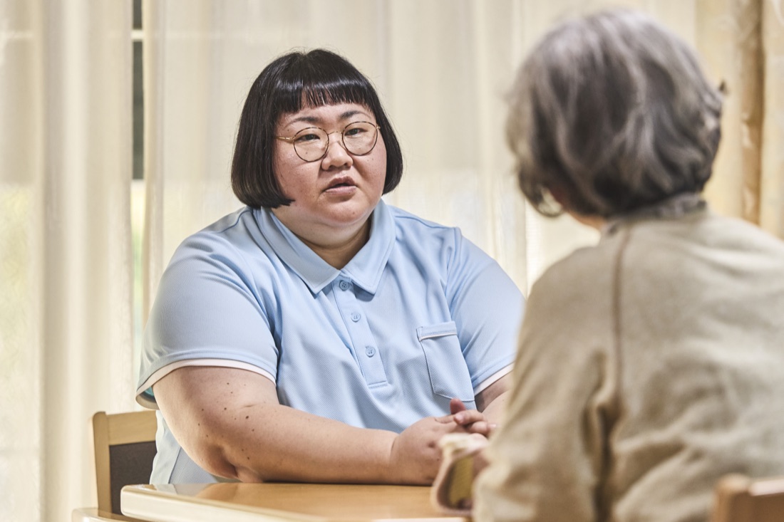 場面写真：入居者の手をとり、笑顔で語りかける介護スタッフ。